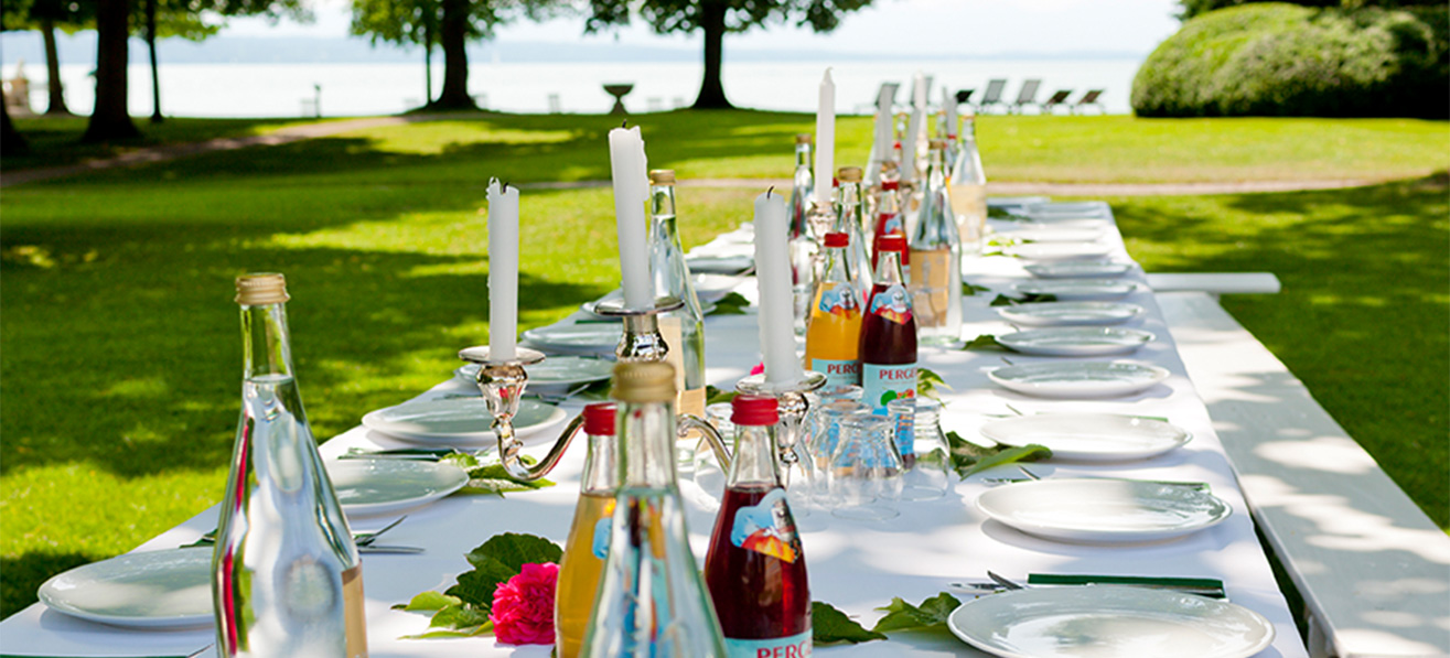 gedeckte Tafel im Schlosspark mit Blick auf See