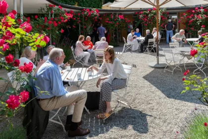 Kaffeepause vor rot blühenden Rosen auf der Terrasse des Restaurants